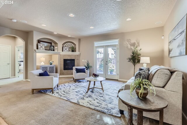 living room with a fireplace, french doors, and a textured ceiling