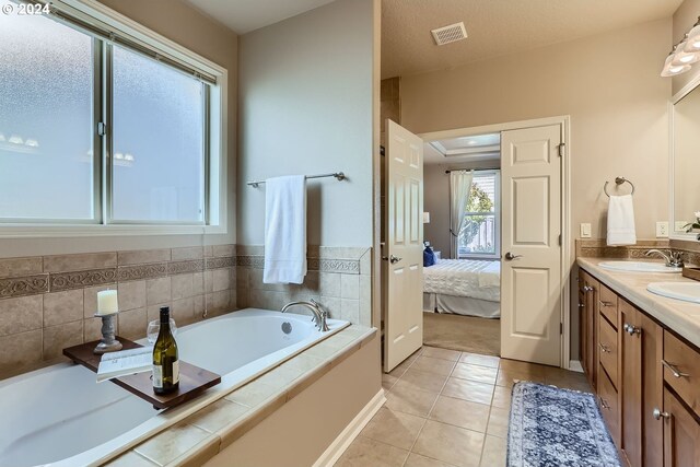 bathroom with tile patterned flooring, vanity, and a bath