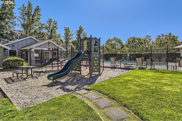 view of jungle gym with a lawn and a community pool