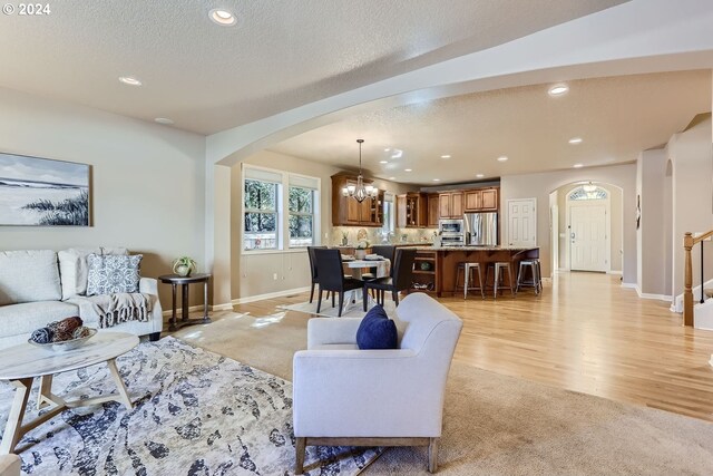 living room featuring a chandelier, a textured ceiling, and light wood-type flooring