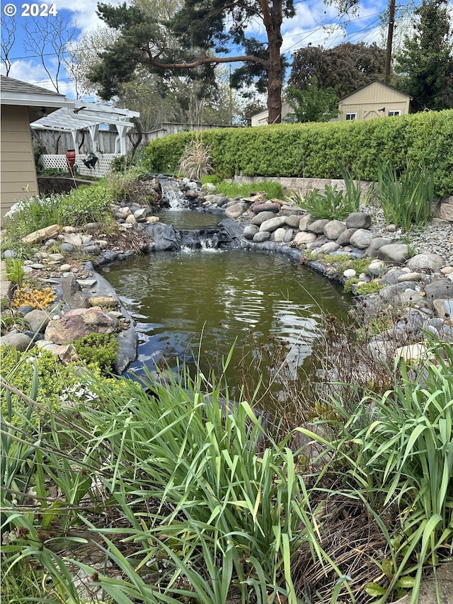 view of yard featuring a small pond and a pergola