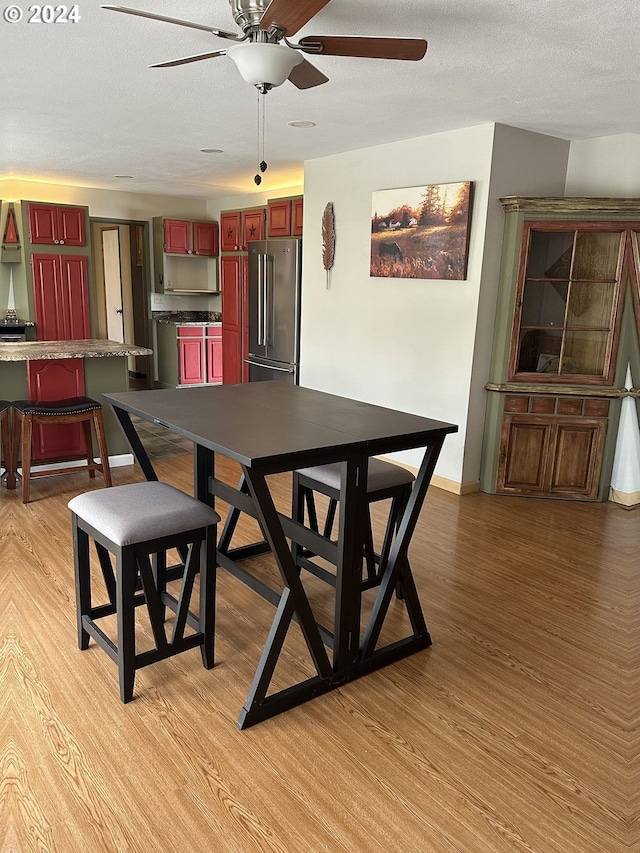 dining room featuring a textured ceiling, ceiling fan, and light hardwood / wood-style flooring