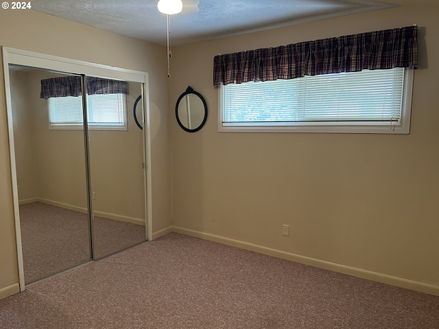 unfurnished bedroom with a textured ceiling, a closet, and carpet flooring