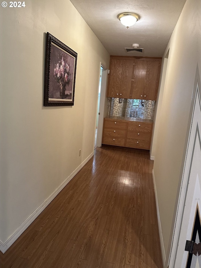 hallway with a textured ceiling and dark hardwood / wood-style flooring