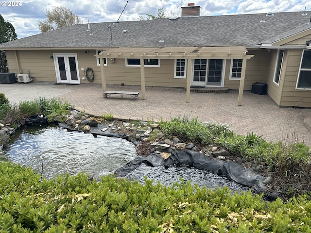 back of house featuring french doors, cooling unit, a small pond, and a patio area