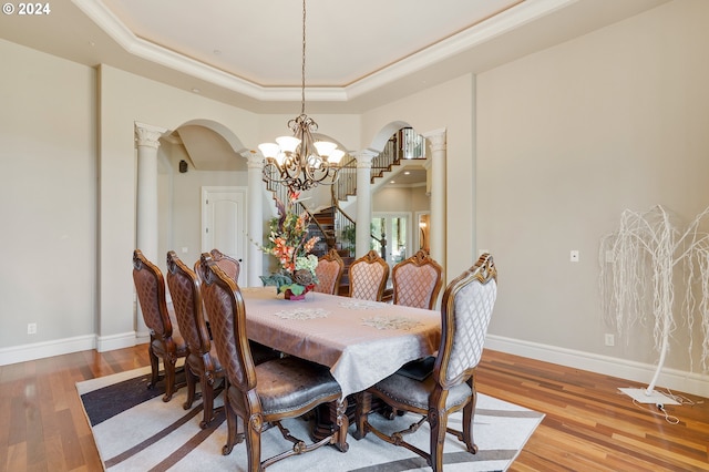 dining space with a tray ceiling, crown molding, a chandelier, and light hardwood / wood-style floors