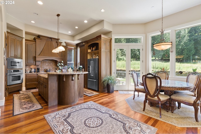 kitchen with a center island, french doors, hanging light fixtures, stainless steel appliances, and tasteful backsplash