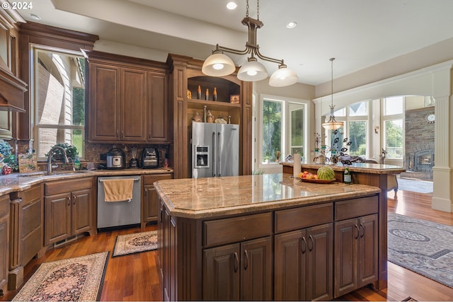 kitchen featuring appliances with stainless steel finishes, light stone counters, sink, light hardwood / wood-style flooring, and a kitchen island