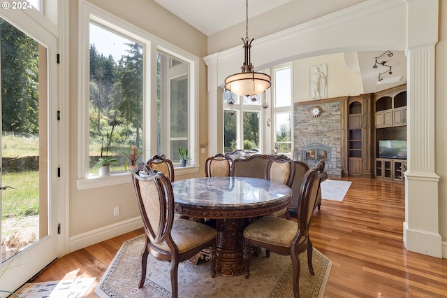 dining area featuring a fireplace, light hardwood / wood-style flooring, and ornate columns