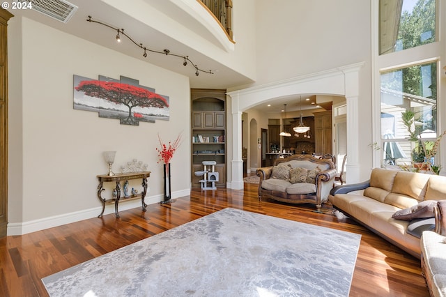 living room featuring hardwood / wood-style flooring, ornate columns, and a high ceiling