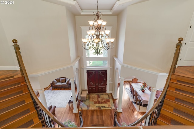 entrance foyer with a raised ceiling, a towering ceiling, wood-type flooring, and a notable chandelier