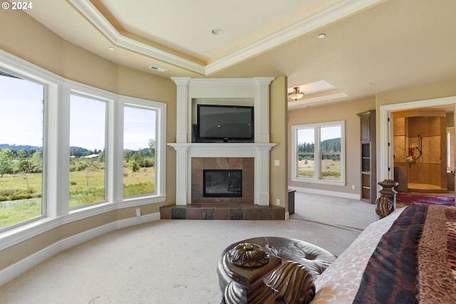 living room featuring light carpet, a tray ceiling, crown molding, and a tiled fireplace