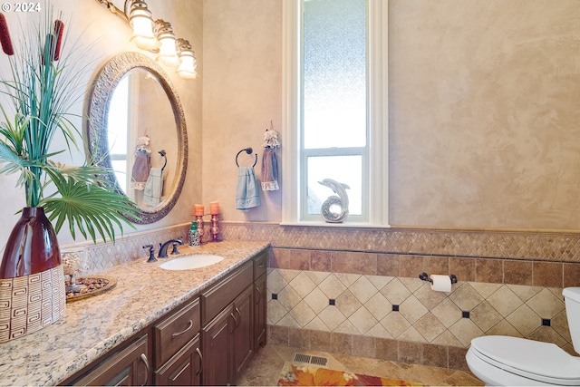 bathroom with vanity, tile walls, and toilet