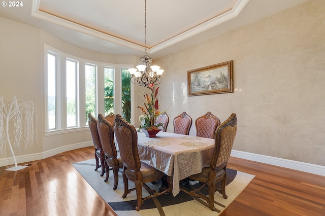 dining space featuring wood-type flooring, a tray ceiling, and a wealth of natural light