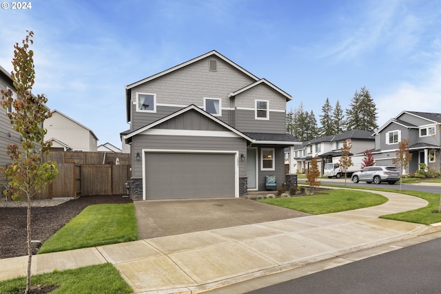 view of front facade with board and batten siding, fence, a garage, stone siding, and driveway