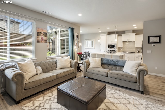 living area with light wood finished floors, visible vents, recessed lighting, and baseboards