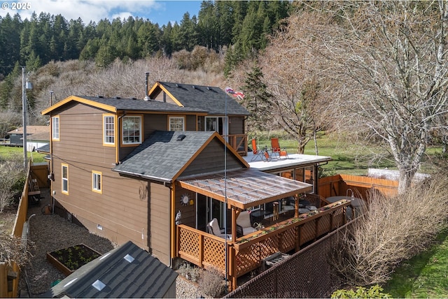 rear view of property featuring a wooden deck and a shingled roof