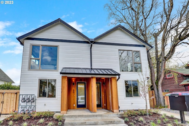 view of front of home featuring covered porch, metal roof, a standing seam roof, and fence