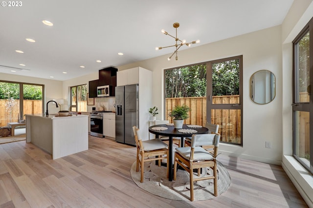 dining room featuring sink, light hardwood / wood-style flooring, and a notable chandelier