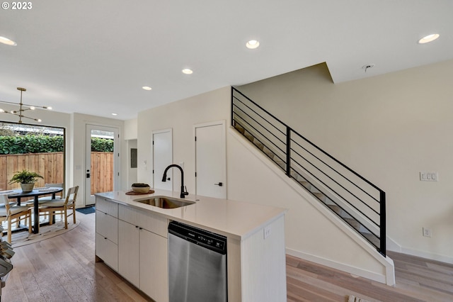 kitchen featuring light wood-style flooring, an island with sink, a sink, light countertops, and stainless steel dishwasher