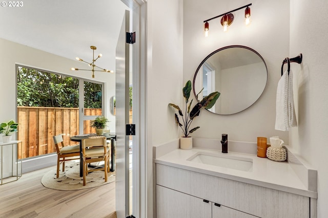 bathroom with an inviting chandelier, vanity, and wood finished floors