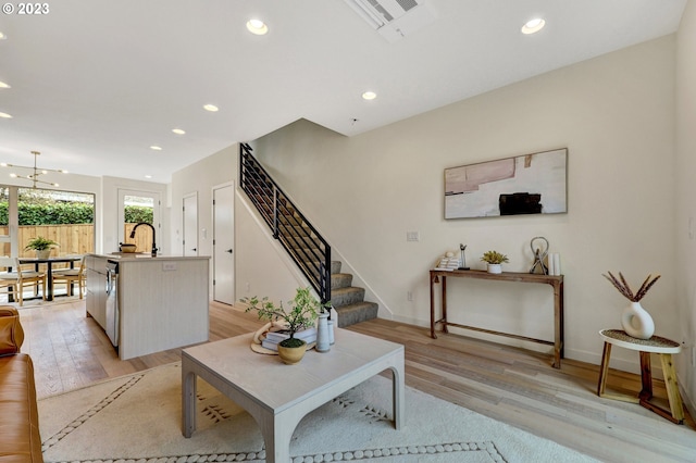 living room featuring stairs, recessed lighting, baseboards, and light wood finished floors