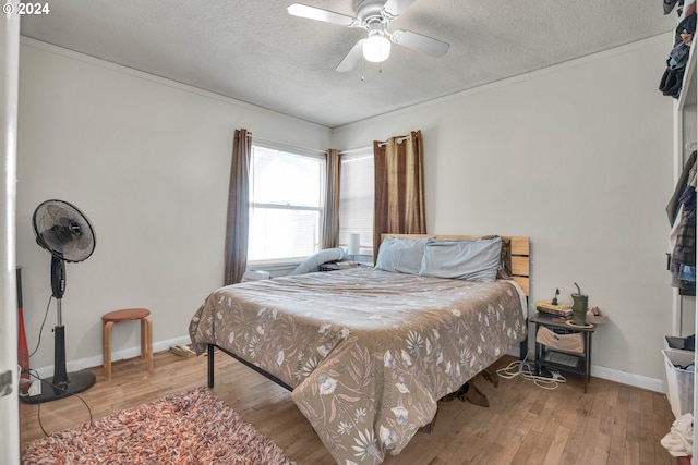 bedroom with a textured ceiling, ceiling fan, and light hardwood / wood-style flooring