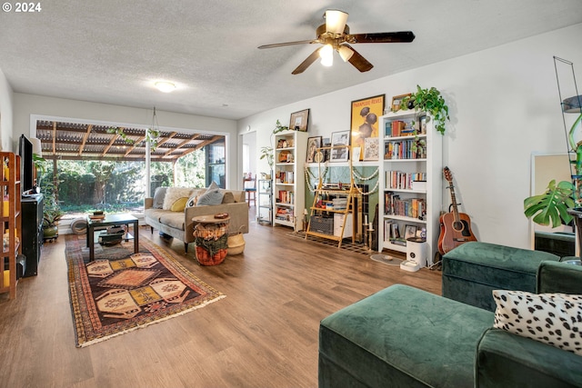 living room with a textured ceiling, ceiling fan, and hardwood / wood-style flooring