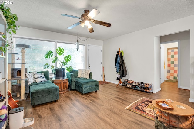 living area featuring ceiling fan, hardwood / wood-style flooring, and a textured ceiling