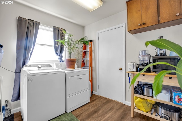 clothes washing area with cabinets, washer and clothes dryer, and dark wood-type flooring