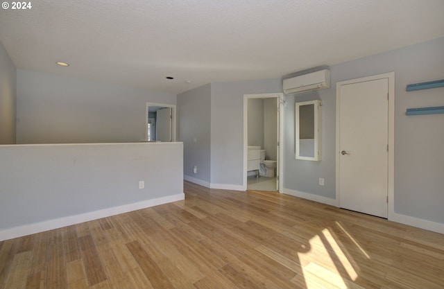 spare room featuring light hardwood / wood-style floors and a wall unit AC