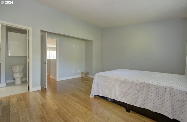 bedroom with hardwood / wood-style flooring and ensuite bathroom