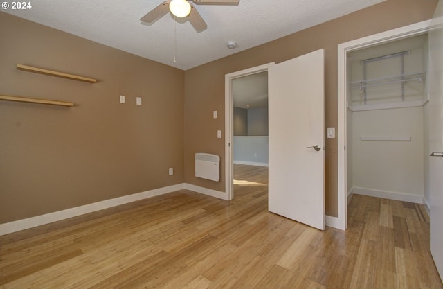 unfurnished bedroom with light wood-type flooring, a textured ceiling, ceiling fan, and a closet