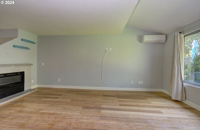 unfurnished living room with a textured ceiling, light wood-type flooring, and a wall unit AC