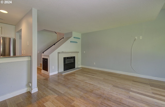 unfurnished living room featuring a textured ceiling and light hardwood / wood-style floors