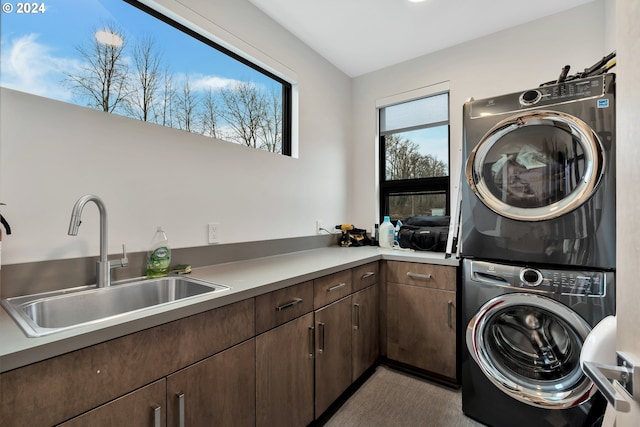 clothes washing area featuring sink, cabinets, and stacked washer / drying machine