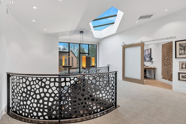 hallway with light carpet and vaulted ceiling with skylight