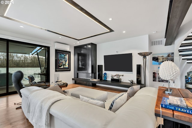 living room featuring light hardwood / wood-style flooring and a wall unit AC