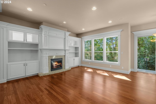 unfurnished living room with built in features, a fireplace, and hardwood / wood-style floors