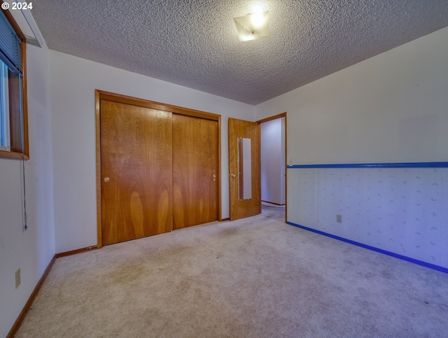 unfurnished bedroom with light colored carpet, a textured ceiling, and a closet