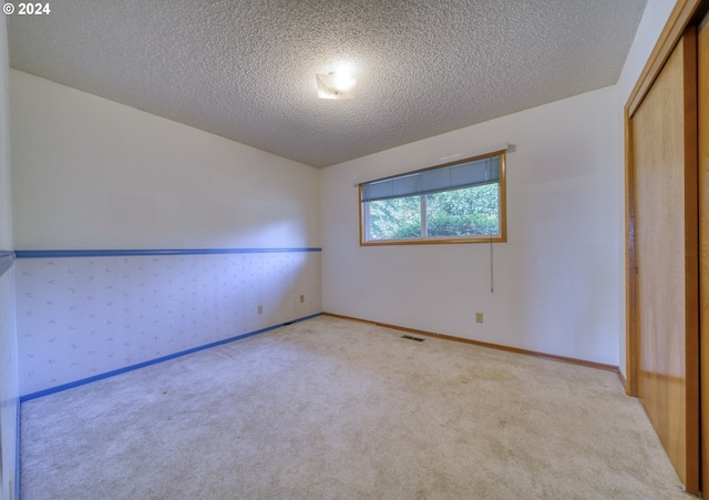 unfurnished bedroom featuring a closet, light colored carpet, and a textured ceiling