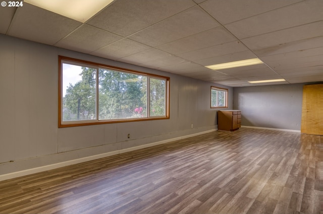 empty room featuring wood-type flooring and a drop ceiling