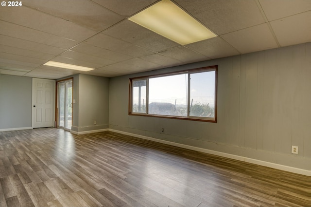 unfurnished room with a drop ceiling and hardwood / wood-style floors