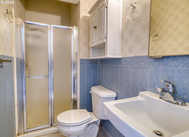 bathroom with toilet, a shower with door, and sink