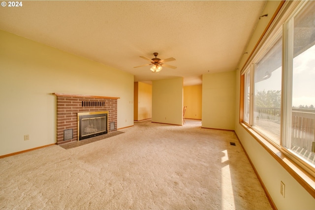 unfurnished living room with ceiling fan, light colored carpet, a textured ceiling, and a brick fireplace