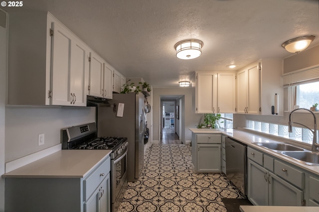 kitchen featuring gray cabinets, light tile patterned flooring, appliances with stainless steel finishes, sink, and a textured ceiling