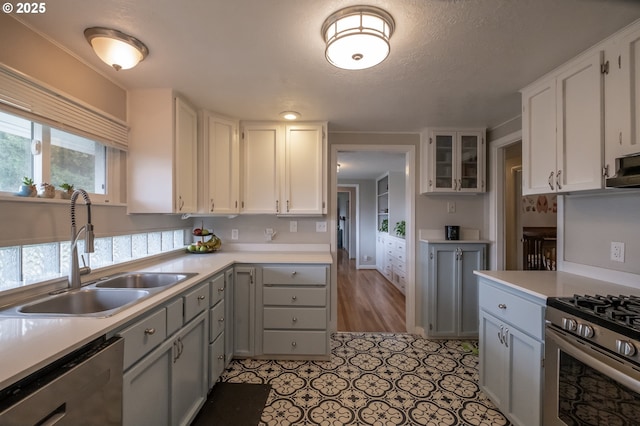 kitchen featuring white cabinetry, sink, light tile patterned floors, stainless steel appliances, and a textured ceiling