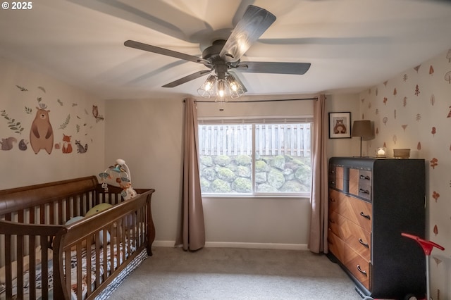 bedroom with carpet floors, a nursery area, and ceiling fan