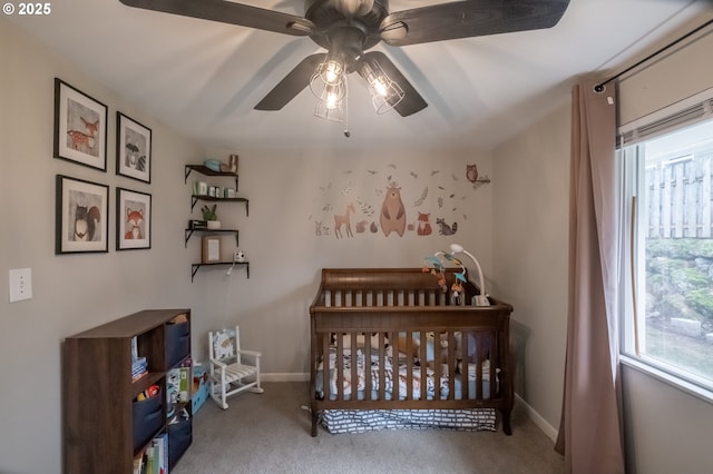 bedroom featuring light carpet, a crib, and ceiling fan