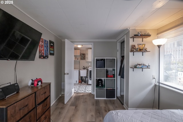 bedroom with multiple windows, crown molding, sink, and light hardwood / wood-style flooring